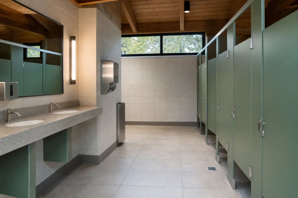 Clean park pavilion restroom with green stalls